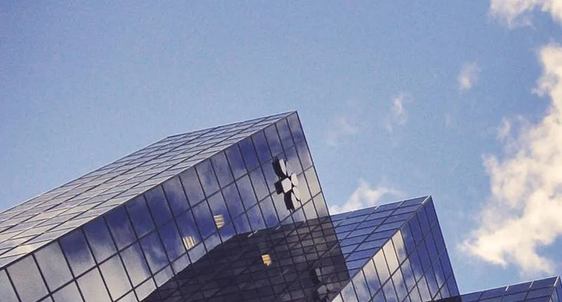 Looking up at glass buildings from the ground.
